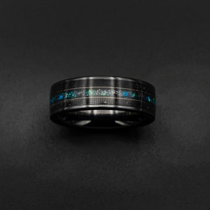 Könnte beinhalten: Ein schwarzer Ring aus Wolframcarbid mit einem dünnen Band aus blauem und grünem Opal-Inlay.