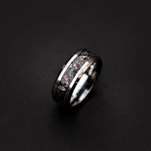 May include: A silver and black tungsten carbide ring with a black and red inlay. The ring has a beveled edge and a polished finish.