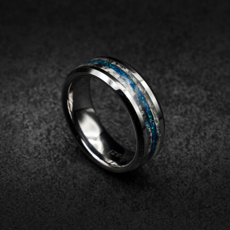 May include: A silver tungsten carbide ring with two blue and white opal inlay bands.