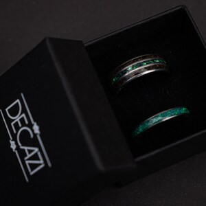 May include: Two black and green rings in a black box with the word "DECAZI" printed on the box.