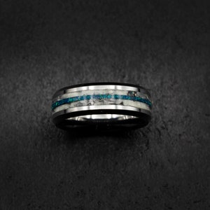 May include: A black tungsten carbide ring with a silver inlay and a thin blue line.