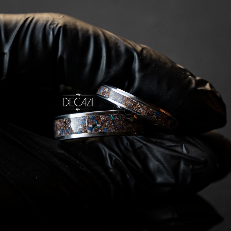 May include: Two silver rings with a dark brown inlay and blue accents. The rings are stacked on top of each other.