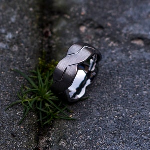 Op de afbeelding: Een donkergrijze gevlochten metalen ring met een geborstelde afwerking.
