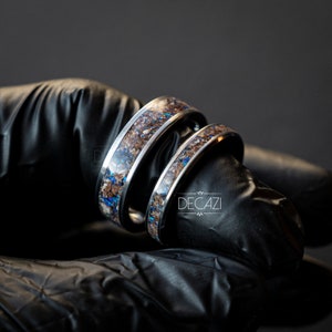 May include: Two silver rings with a brown and blue inlay. The rings are stacked on top of each other.