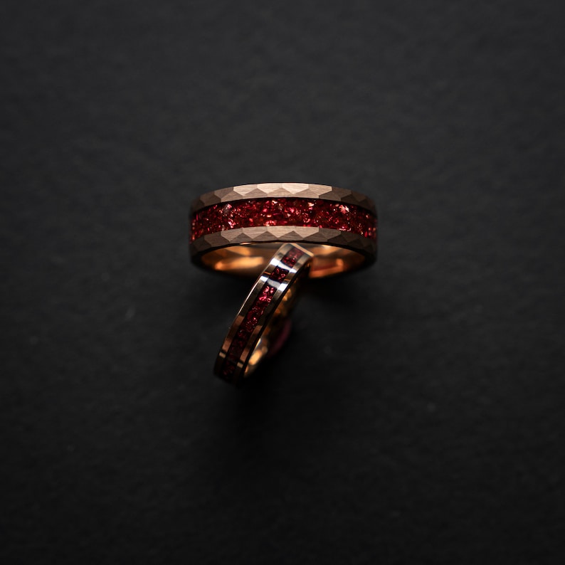 K&ouml;nnte beinhalten: Zwei goldene Ringe mit einem roten Edelstein-Inlay. Die Ringe sind &uuml;bereinander gestapelt.