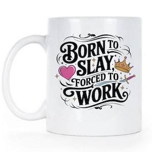 May include: White ceramic mug featuring a black and white graphic design that reads "Born to Slay, Forced to Work". The design also includes a pink heart, a gold crown, and a silver dagger.