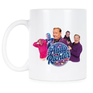 May include: White ceramic mug featuring a colorful graphic of Andy Richter and the text "Andy Richter" on a disco ball. The mug has a large handle and is suitable for hot or cold beverages.