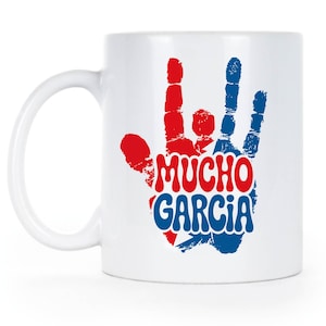 May include: White ceramic mug with a red and blue handprint design. The handprint is filled with the colors of the Puerto Rican flag and the words "MUCHO GARCIA" in a retro font. The mug has a white handle.