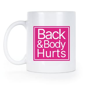 May include: White ceramic coffee mug with a pink square that says "Back & Body Hurts" in white text.