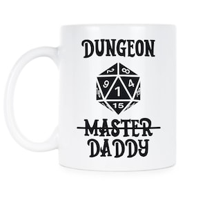 Puede incluir: Taza de cerámica blanca con un gráfico negro de un dado de veinte caras y el texto "Dungeon Master Daddy".