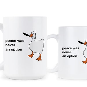 May include: Two white ceramic mugs with a black and white illustration of a goose holding a knife. The text on the mugs reads "peace was never an option".