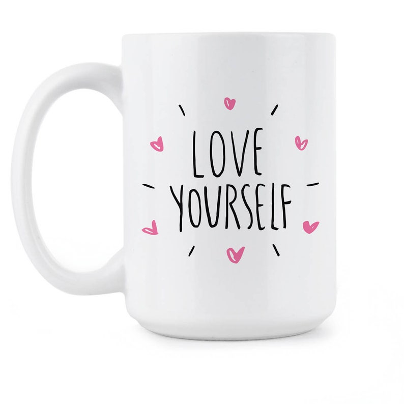 May include: White ceramic coffee mug with a black and pink design. The mug features the text "LOVE YOURSELF" surrounded by pink hearts.