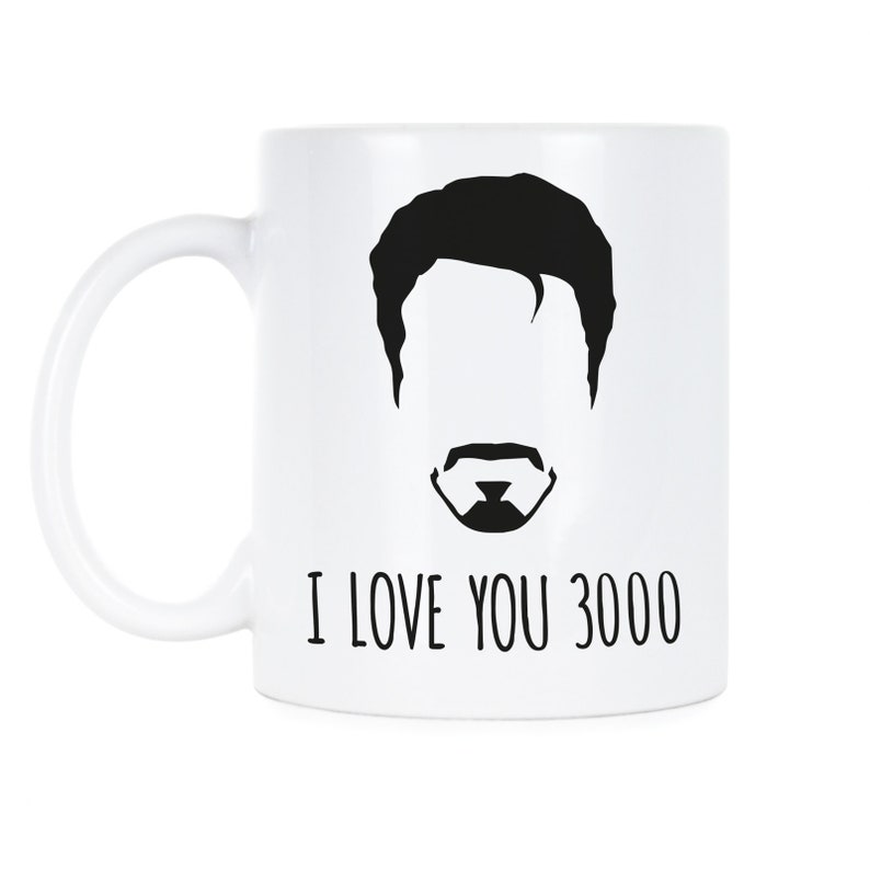 May include: White ceramic mug with a black silhouette of a man's face and the text "I love you 3000".