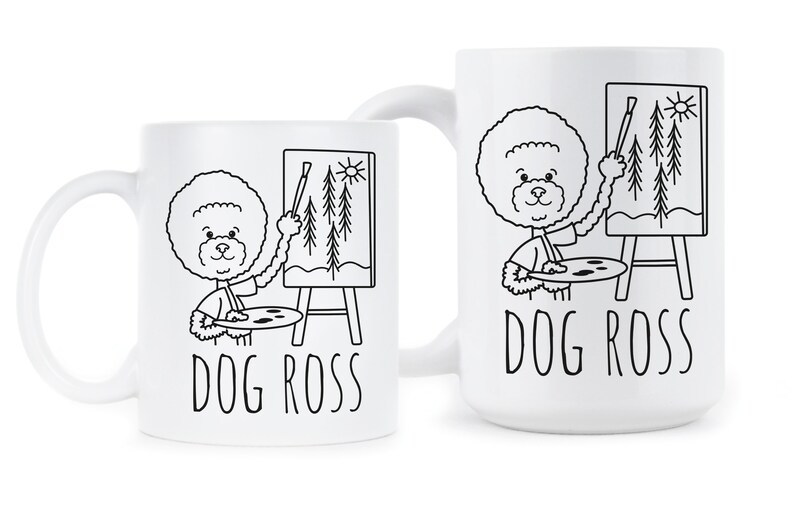 May include: Two white ceramic mugs with black outlines of a dog painting a picture of trees. The text "DOG ROSS" is printed on both mugs.