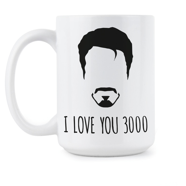 May include: White ceramic coffee mug with a black silhouette of a man's face with a mustache and the text "I love you 3000".