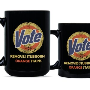 May include: Two black coffee mugs with a vintage-style logo that says "Vote" in a blue and yellow circle with an orange ring around it. The text below the logo says "Removes Stubborn Orange Stains".