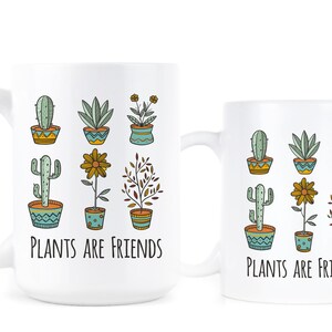 May include: Two white ceramic mugs with a black outline of various potted plants and the text "Plants are Friends".