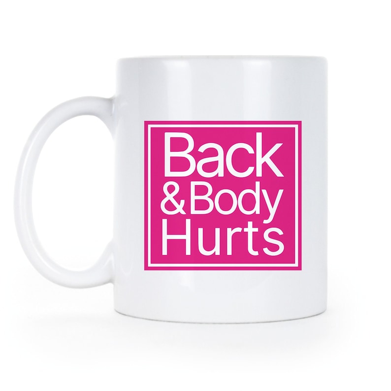 May include: White ceramic coffee mug with a pink square that says "Back & Body Hurts" in white text.