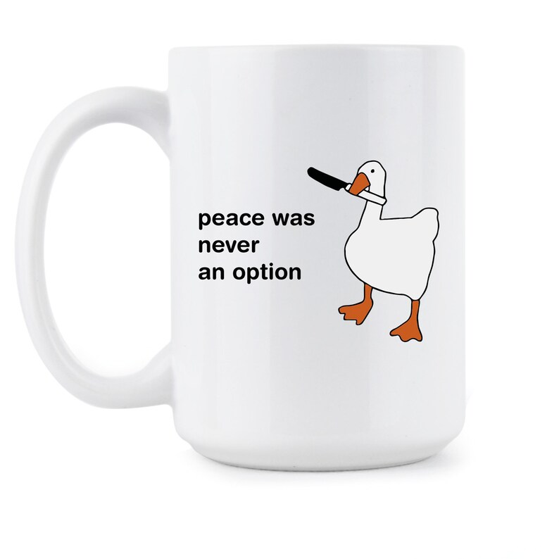 May include: White ceramic mug with a black and white illustration of a goose holding a knife in its beak. The text "peace was never an option" is printed on the mug.