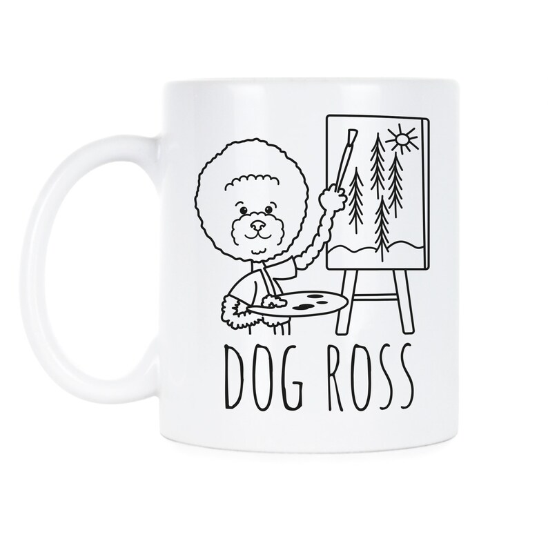 May include: White ceramic coffee mug with a black line drawing of a dog holding a paintbrush and palette. The dog is painting a landscape with trees and a sun. The text "DOG ROSS" is printed below the image.