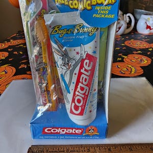 May include: A blue and white box with a Bugs Bunny themed Colgate toothpaste and toothbrush set. The box says "Free Comic Book Inside This Package". The toothpaste is bubble fruit flavored. The toothbrush is extra soft and for ages 3-8.
