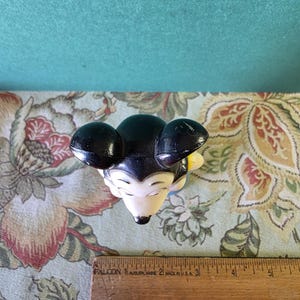 May include: Black and white plastic Mickey Mouse figurine with yellow accents. The figurine is approximately 4 inches tall.