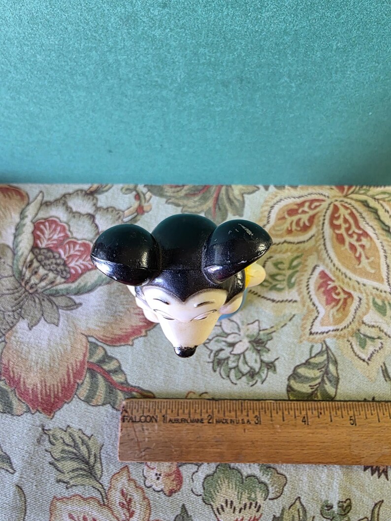 May include: Black and white plastic Mickey Mouse figurine with yellow accents. The figurine is approximately 4 inches tall.