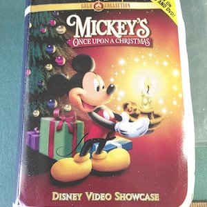 May include: A DVD case for "Mickey's Once Upon a Christmas" from the Walt Disney Gold Collection. The cover features Mickey Mouse, Christmas presents, and a Christmas tree. The case is red and gold with the text "Disney Video Showcase".