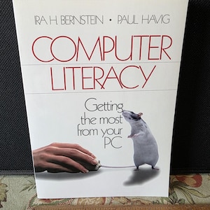 May include: A book titled "COMPUTER LITERACY" with the subtitle "Getting the most from your PC." The cover features a white rat standing next to a computer mouse. The author's names are Ira H. Bernstein and Paul Havig.