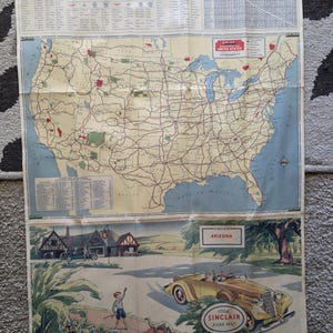 May include: A 1934 Sinclair road map of the United States featuring a detailed highway network, a mileage chart, and an index. The bottom section displays a vintage illustration of a yellow convertible car and a child, with a ruler showing 21 inches.