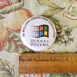 May include: A white button with a blue and green Microsoft Windows logo and the text "40 Million Users and Counting!"  The button is on a floral fabric background.