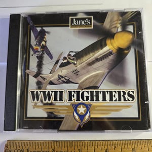 May include: A CD case for "Jane's WWII Fighters" combat simulation game. The cover features a detailed illustration of a WWII fighter plane with a yellow nose and propeller, and another plane in the background. The title is in bold white letters.