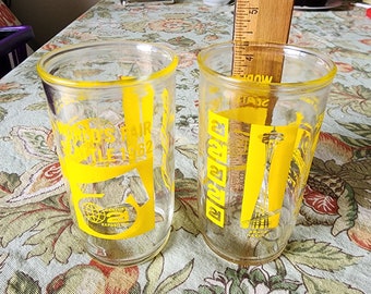 May include: Two clear glass tumblers with yellow graphics. The glasses feature the text "Century 21 Exposition" and "Seattle World's Fair 62".