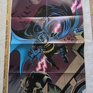 May include: Batman poster featuring the superhero in a dynamic pose with a dark purple background and lightning. The poster includes the text "BATMAN" at the top and "THE DARK KNIGHT RETURNS EVERY MONTH IN" at the bottom, along with the DC Comics logo.