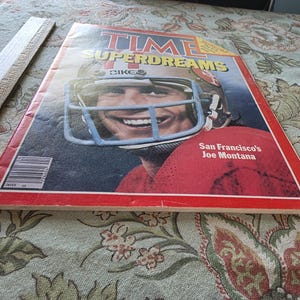 May include: A vintage TIME magazine cover featuring a smiling football player in a helmet. The cover has the title "SUPERDREAMS" and the text "San Francisco's Joe Montana" on a red background.
