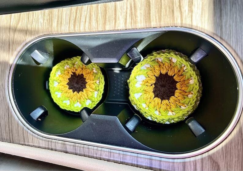 Pu&ograve; includere: Due sottobicchieri rotondi all'uncinetto con un design ispirato ai girasoli. Ogni sottobicchiere presenta un centro marrone scuro circondato da strati di petali in filato giallo e verde chiaro, creando un motivo floreale circolare per portabicchieri.