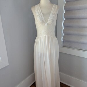 May include: Ivory-colored, sleeveless nightgown with a V-neckline. The bodice and neckline are adorned with delicate white lace. The flowing skirt drapes to the floor. The nightgown is displayed on a mannequin.