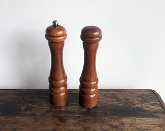 Può includere: Un set di due macinini per sale e pepe in legno con finitura marrone scuro. I macinini hanno un design classico con una parte superiore rotonda e un corpo cilindrico.