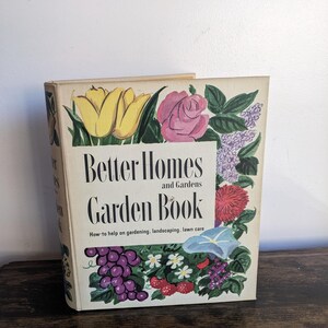 May include: Vintage "Better Homes and Gardens Garden Book" with floral illustrations. The cover features a yellow tulip, pink rose, and various other flowers and fruits. The book's title and subtitle are displayed in black text.