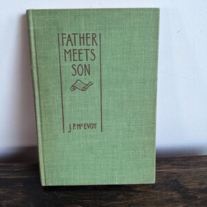 May include: A green book with the title "Father Meets Son" and the author's name "J.P. McEvoy" printed on the cover.
