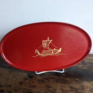 以下が含まれることがあります： 船と人々が描かれた金のデザインが施された赤い楕円形のトレイ