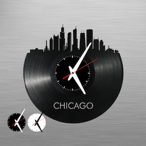 May include: Black vinyl record clock with a white silhouette of the Chicago skyline and the word "CHICAGO" printed below. The clock face has white hands and a black background.
