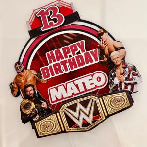 Peut inclure: Une décoration de gâteau sur le thème de la WWE avec le chiffre 13, le texte HAPPY BIRTHDAY MATEO, des images des catcheurs Rey Mysterio, Roman Reigns, John Cena et Cody Rhodes, et une ceinture de champion WWE dorée en bas.