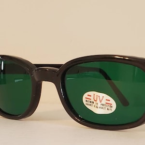May include: Black plastic sunglasses with green lenses. The sunglasses have a label that reads "UV - Maximum UV Protection Against Ultra Violet Rays".