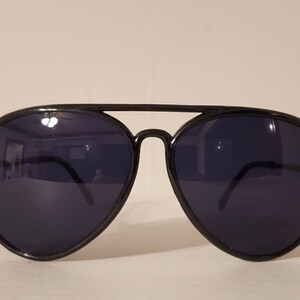 May include: Black aviator sunglasses with dark lenses. The sunglasses have a metal frame and are in good condition.
