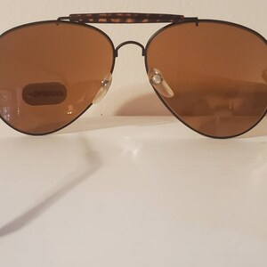 May include: Black aviator sunglasses with brown lenses and a tortoise shell bridge. The sunglasses have a metal frame and are in good condition.