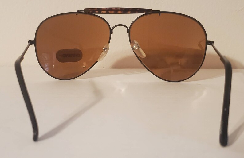 May include: Black aviator sunglasses with brown lenses and a tortoise shell bridge. The sunglasses have a metal frame and are in good condition.