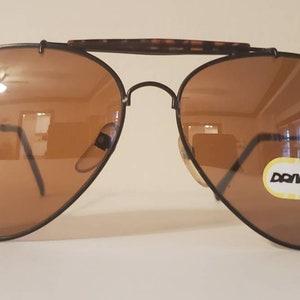 May include: Black aviator sunglasses with brown lenses and a brown tortoise shell frame. The sunglasses have a "Donwing" label on the right lens.
