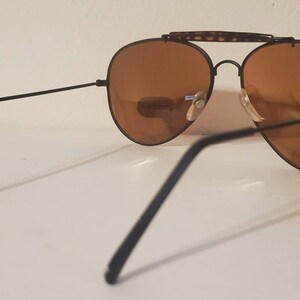 May include: Black aviator sunglasses with brown lenses and a tortoise shell bridge.