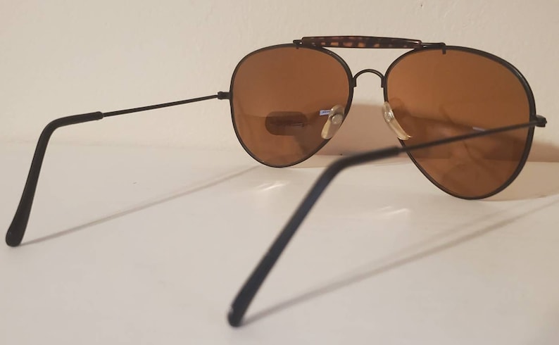 May include: Black aviator sunglasses with brown lenses and a tortoise shell bridge.